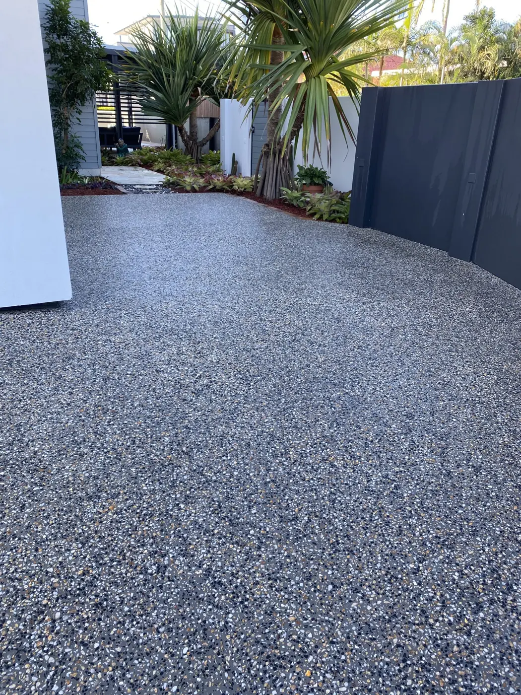 Charcoal sealed concrete driveway with dark stone