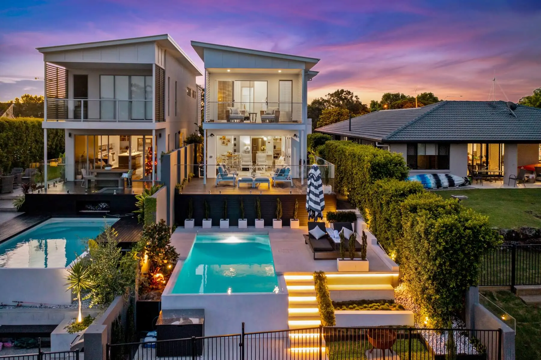 Concrete pool surround and lit floating steps at a two-storey Gold Coast home at dusk