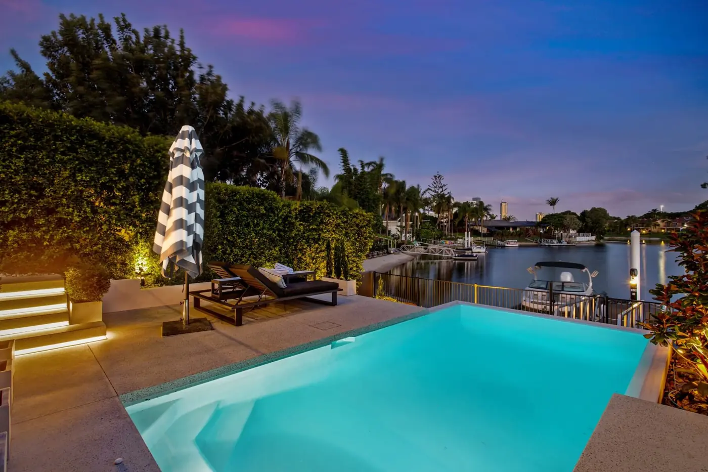 Pool surround and lit steps at dusk on a canal