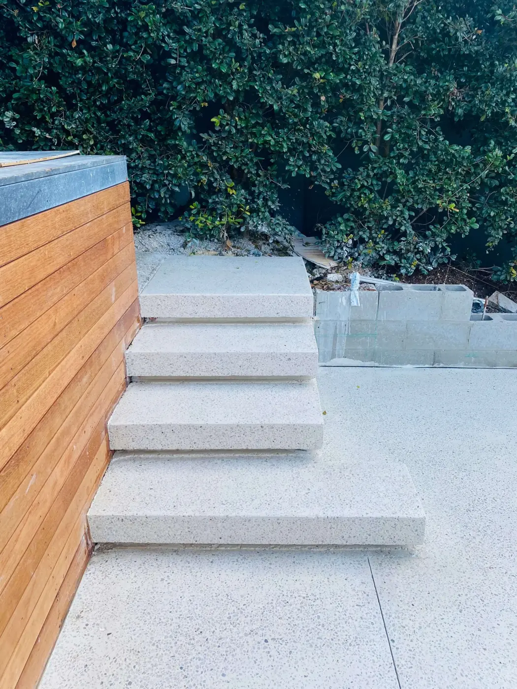 Floating concrete steps against a timber wall